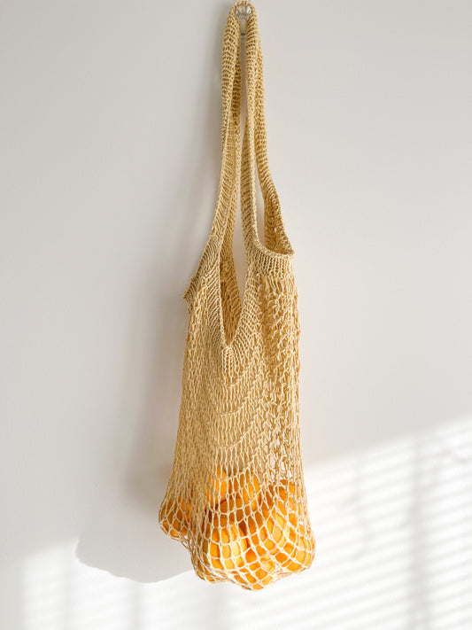 Yellow Knit French style market string bag with oranges inside 